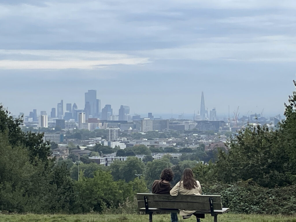 Eine Bank mit einem Paar in Hampstead Heath mit Blick auf Londons Skyline